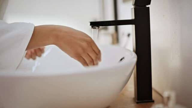 Lady fingers opening tap in home bathroom closeup. African brunette washing face