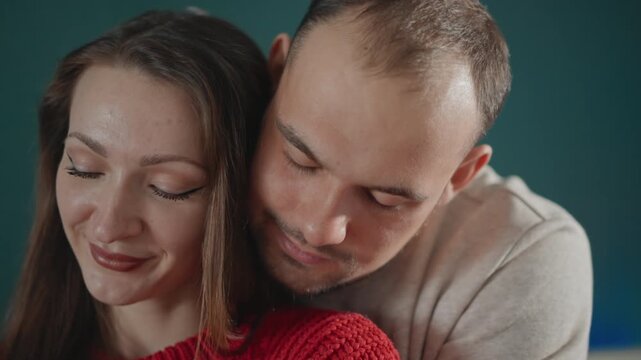 Tight close-up shows young couple sharing affectionate embrace, with man leaning over woman's shoulder, soft head tilt, relaxed expressions, gentle touch, and warm romantic mood, with couple, embrace