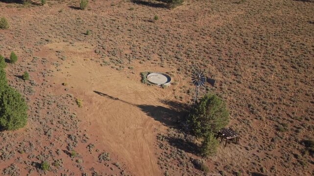Aerial partial orbit of defunct windmill and stock tank on arid rangeland at Dow Wells, Lassen County, California.