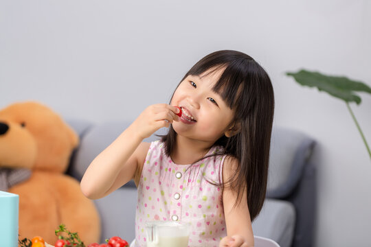 Asian little girl eating fresh cherry tomatoes, healthy diet and nutrition concept
