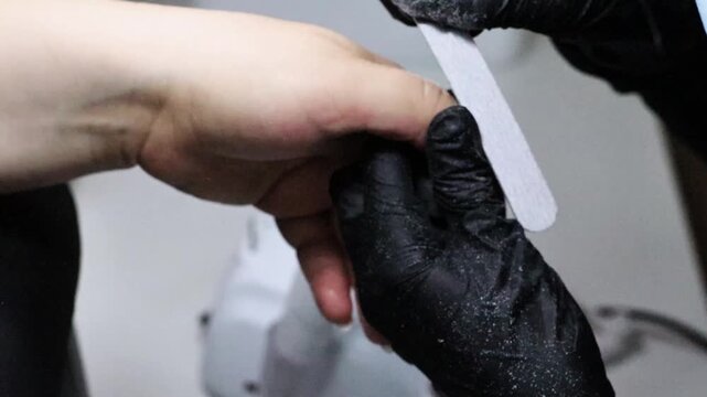 Getting her nails done at a beauty salon, a woman has her nail shape refined with a file. Lifestyle footage for beauty, fashion, grooming, personal care, salon services and everyday style.