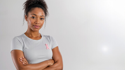 Obraz premium Confident Black woman wearing a pink ribbon on her t-shirt. Breast cancer awareness and support concept. Copy space for text