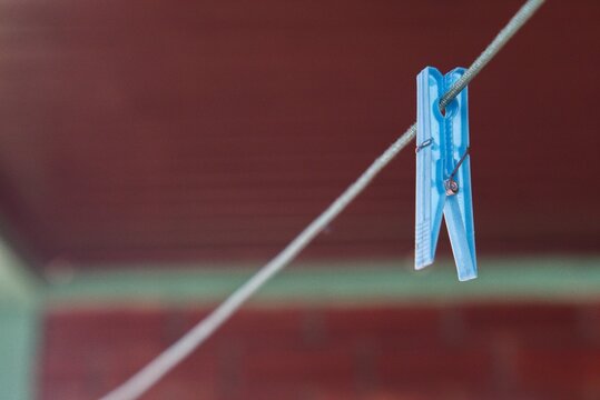 Clothes peg hanging on a clothesline, used to secure garments while drying outdoors.
