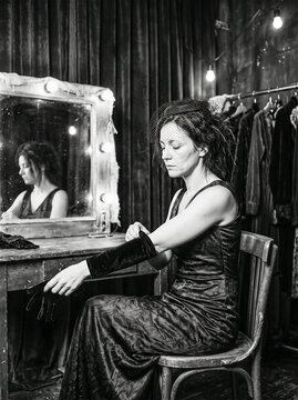 Black and white photo of elegant actress sitting at vanity mirror in dressing room