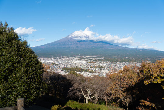 A scenic panoramic view of snow-capped Mount Fuji overlooking Fujinomiya city from Shirao Mountain Park (Shiraosan) on a sunny December afternoon. Horizontal shot.