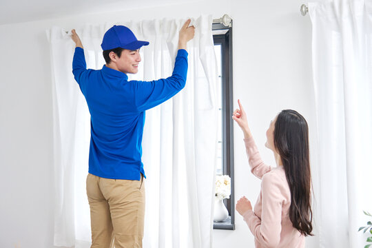 引っ越し業者がカーテンを取り付け女性が指示する