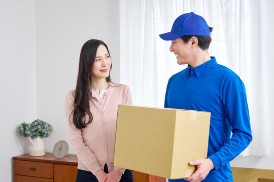 目を合わせる段ボールを持つ笑顔の引っ越し業者と女性