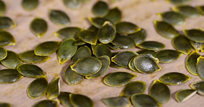Fresh green pumpkin seeds on a paper background, the natural texture of pumpkin seeds laid out on a culinary paper background at home during drying 