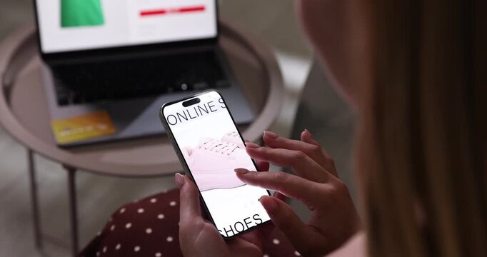 Online store. Woman with credit card using laptop and smartphone at table indoors, closeup