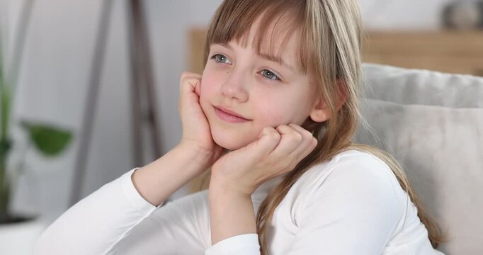 Pensive little girl on sofa at home