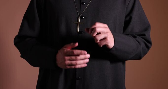 Priest gesturing on beige background, closeup. Camera moving forward