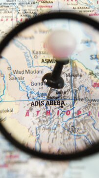 Magnifying glass finding Addis Ababa on a paper map