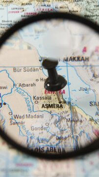 Magnifying glass locating Asmara on a printed map