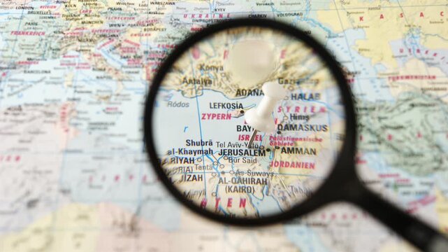 Magnifying glass finding Jerusalem on a printed paper map