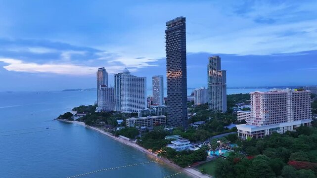 An aerial view of the Pattaya waterfront with modern high-rise condominiums and hotels directly on the beach and calm turquoise sea.