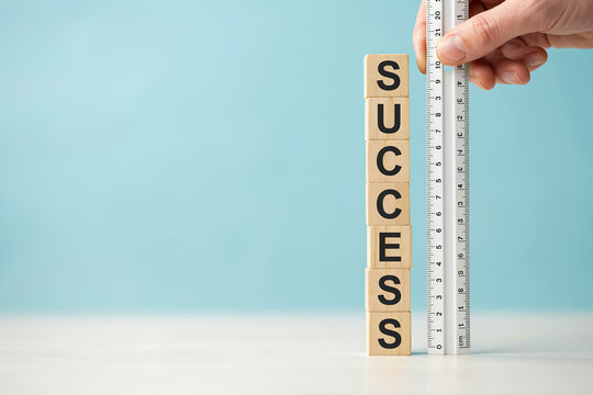 Hand measuring a stack of wooden blocks with the word success written on them measurement business achievement progress planning strategy development performance benchmark analysis