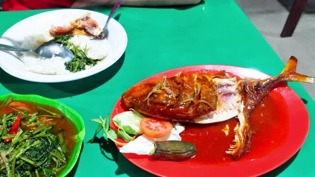 dinner, on the plate there is sea fish with sour and sweet sauce and a plate of stir-fried water spinach, very delicious