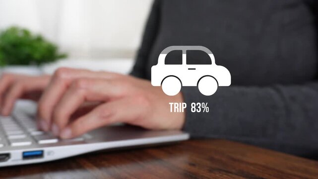 Close-up of a woman working on a computer, pointing at a loading animation featuring a percentage counter, a car graphic, and the word "Trip."