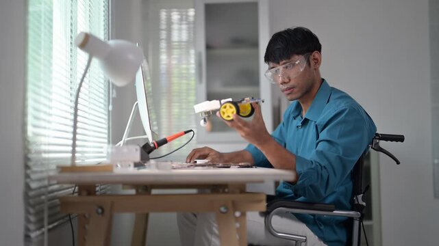 Asian engineer assembling robotics components in wheelchair
