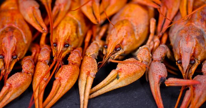 A pile of red boiled crayfish on a black table, whole hard-shelled boiled crayfish stacked together on the kitchen table