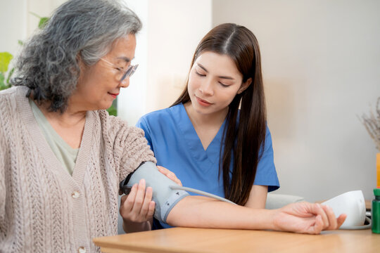 Asian woman nurse measuring blood pressure senior patient, medical checking for hypertension monitoring, caregiver support elderly woman with arterial blood pressure device, routine health checkup.