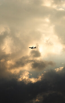 Silueta de avi&oacute;n volando a trav&eacute;s de nubes dram&aacute;ticas al atardecer | Airplane silhouette flying through dramatic clouds at sunset