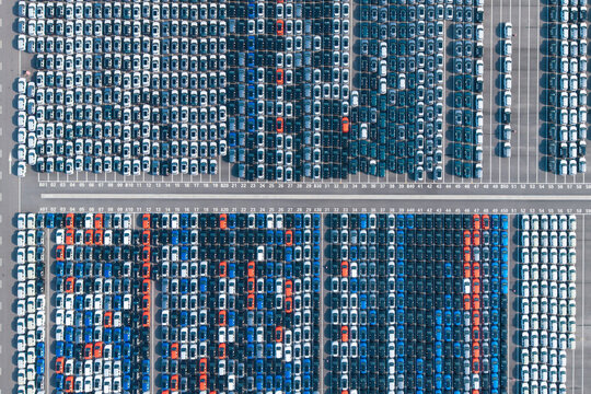 Aerial top‑down view of massive new car storage lot with neatly arranged vehicles