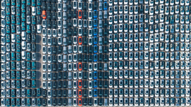 Aerial top‑down view of massive new car storage lot with neatly arranged vehicles