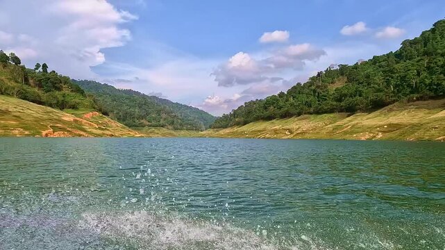 Moving boat tour on a large reservoir with splashing water and mountain view at Khun Dan Prakan Chon Dam in Nakhon Nayok, Thailand