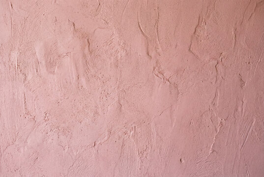 Close up of textured wall painted in muted pink hue