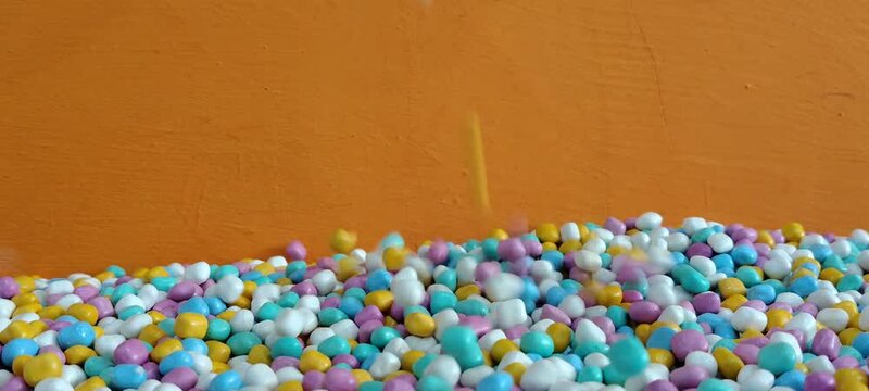 Colorful Candy Sprinkles Falling Down on Orange Background.