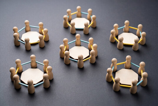 Wooden figures arranged in isolated groups showing organizational silos in dark setting