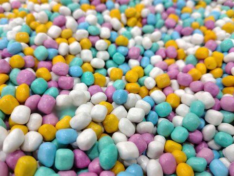 A vibrant, colorful, and textured close-up of a pile of small, round candies.