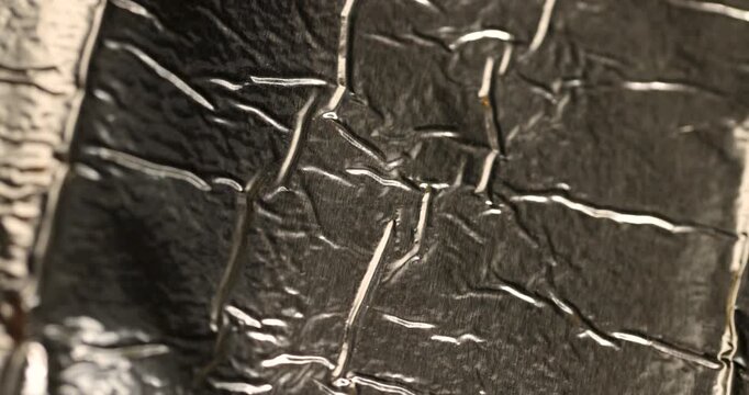 Shiny metallic foil background pattern, crumpled aluminum foil material with fine dark specks on creased gold silver surface