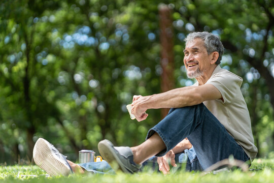 elderly pensioner man spend leisure time relaxing in urban park,sitting and surfing internet on smartphone