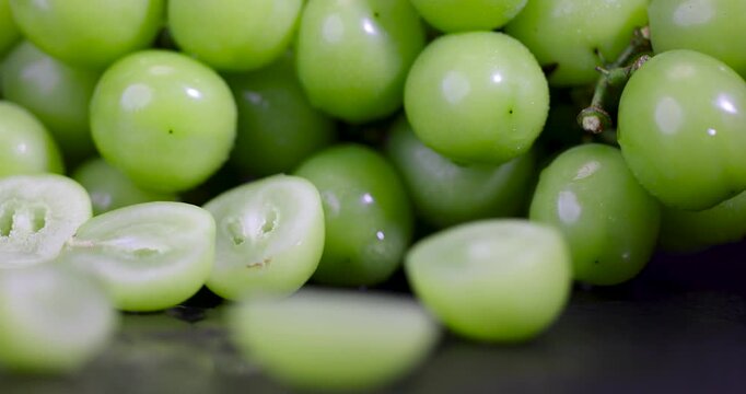 Juicy halves of green grapes inside a pile of berries, slices of sliced green grapes show a seedless core on the counter of the grocery market