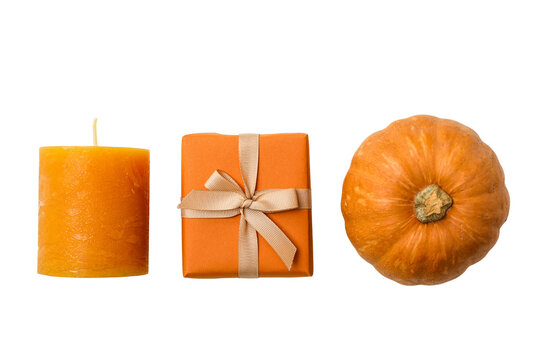 Arrangement of orange candle, present, and pumpkin creates festive scene, PNG