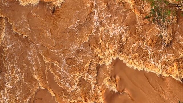 Aerial view of powerful muddy floodwater currents, illustrating extreme weather impacts, climate change risks, watershed disruption, and global challenges in flood resilience and disaster management.
