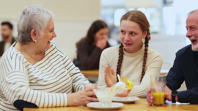 Grandparents and teenage girl sitting at table in cafe. Light snack or coffee break at restaurant, family getaway or pastime. Family time, Sunday lunch at chain cafe 