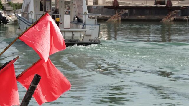 Tourist Boat Departing Cassis Harbor with Red Flags in Foreground