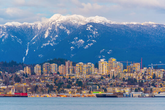 Panoramic view of Vancouver skyline with snow-capped mountains, waterfront, and a small motorboat