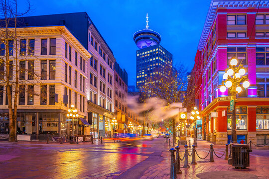 Famous steam clock emitting plume of steam on historic brick street during twilight in Gastown, Vancouver