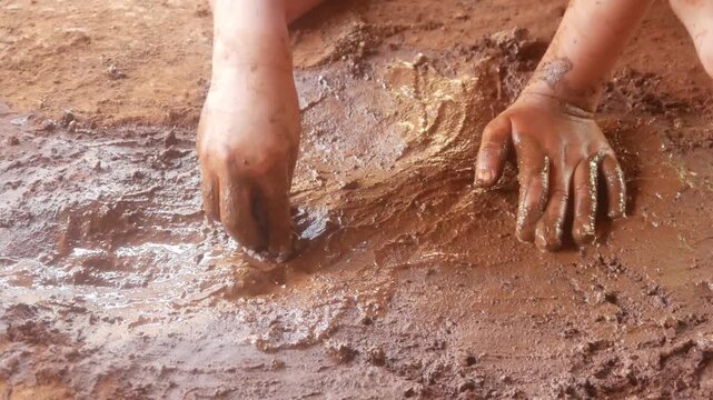 Hands of a small child playing in wet mud
