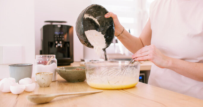 Pastry making. Culinary process. Woman baker hand pouring flour portion in bowl measuring ingredient for tasty homemade dish.