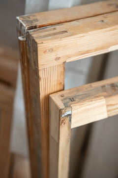 Several frames in restoration workshop with new wooden patches and restored parts standing in room, antique wooden frames collected in woodworking studio, process of restoring and furniture renovation