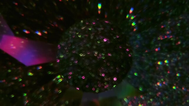 Defocused optical twinkle. Neon glimmer art. Defocused purple pink yellow color lens glitter flare round kaleidoscope floating on visual abstract dark black background.