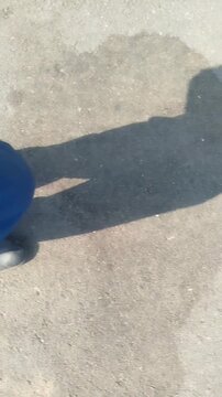 a man wearing trousers and shoes is walking briskly in asphalt street