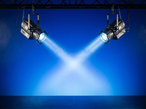 Two blue stage spotlights converging beams against dark background with spotlight lighting equipment performance illumination production technology abstract