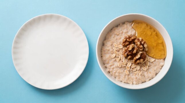 Healthy breakfast oatmeal topped with walnuts honey and fresh fruit in minimalist white bowl