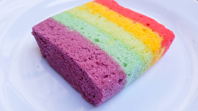 Close up of Colorful Rainbow Layer Cake Slice Served on White Plate